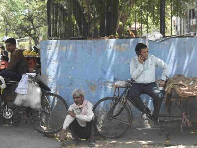 Pedestrians seek refuge under tree shade as temperatures soar in the afternoon.