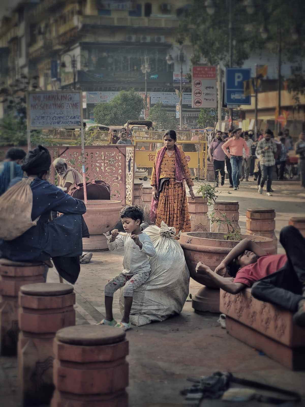 Children: A Moment’s Respite: A boy sits atop the waste his family collects, enjoying an ice cream while his family rests nearby. In this brief moment of sweetness, his face reveals a rare glimpse of contentment amid a life of hardship