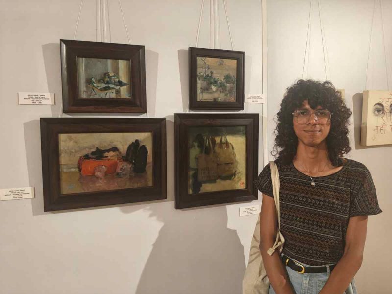 Artist Ember stands beside her works